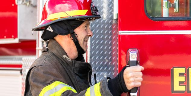 A firefighter opens the door to a fire truck.