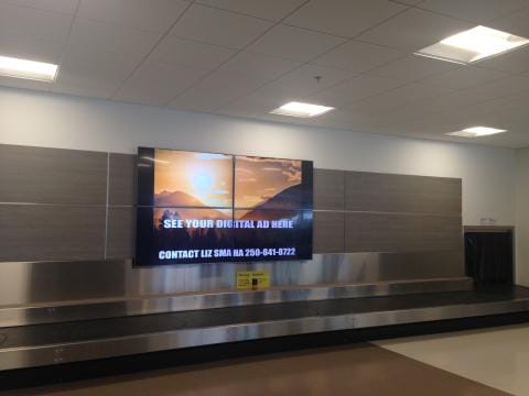 A TV monitor showing an ad above a luggage carousel